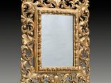 an ornately carved mirror with a gold frame on a black background