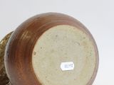 a brown and white vase sitting on a white surface
