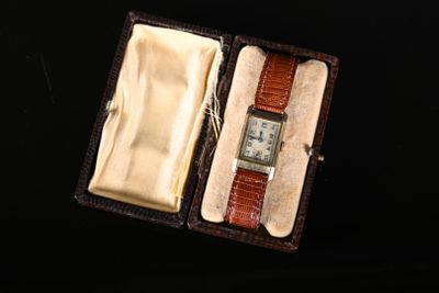 une petite boîte contenant une montre, posée sur une surface noire