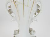 a white vase that has a gold decoration on it