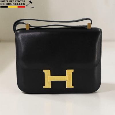 sac à main en cuir noir orné d'un logo « h » doré sur le devant