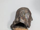 sculpture of a man ' s head on a wooden stand
