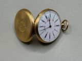 une montre de poche en or posée sur une surface blanche