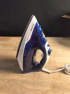 un fer à repasser bleu et blanc posé sur une table en bois