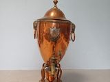 a large copper urn sitting on a wooden stand