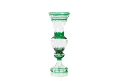 un vase en verre vert posé sur une surface blanche