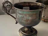 a silver cup sitting on a table next to other silver cups