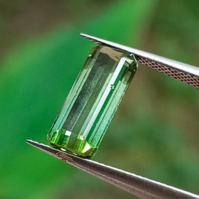 un gros plan sur un morceau de verre vert tenu par une pince