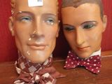 deux têtes de mannequin posées sur une table, avec un mur rouge en arrière-plan