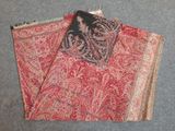 two pieces of red and black paisley fabric on a gray surface