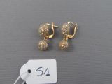 pair of gold tone earrings and a price tag on a gray surface