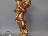 a gold statue of a child holding a lamp on a table