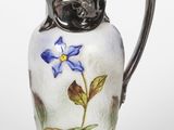 un pichet en verre orné d'une fleur bleue