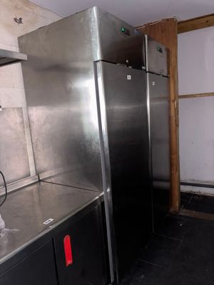 stainless steel refrigerators in a kitchen with black flooring and walls