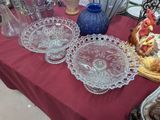 plusieurs plats et vases en verre posés sur une table recouverte d'une nappe rouge