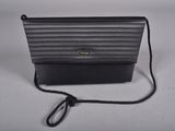 a black purse with a cord attached to it sitting on a table
