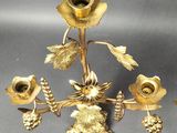 a gold candle holder with a bunch of flowers on it