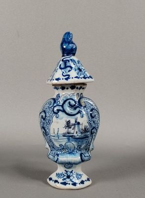 un vase bleu et blanc surmonté d'un oiseau
