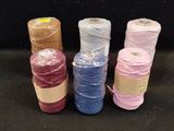 four spools of different colors of thread on a black surface