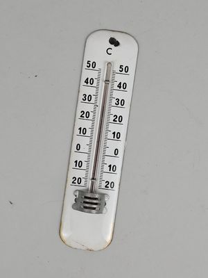 un thermomètre posé sur une surface blanche, avec un arrière-plan noir et blanc