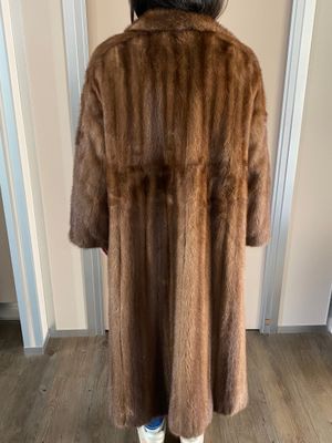 the woman is wearing a brown fur coat and white sneakers