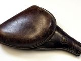 un étui en cuir marron muni d'une poignée en cuir, posé sur une surface blanche