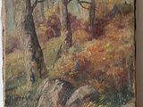 peinture représentant un paysage boisé avec des arbres et des rochers, posée sur une table en bois