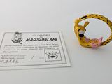 une bague jaune ornée d'une fleur rose, posée à côté d'une carte