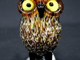 une figurine de chouette posée sur un socle en verre