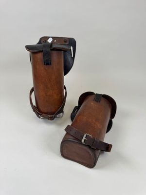 une paire d'étuis en cuir marron munis de lanières, sur fond blanc