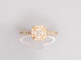 une bague en or jaune sertie d'un diamant rond au centre, entouré de petits diamants blancs