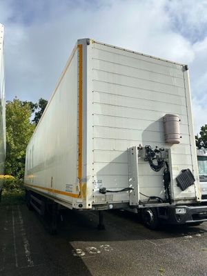 un camion blanc garé sur un parking à côté d'un immeuble