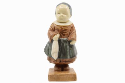figurine représentant une femme tenant un sac, posée sur un socle en bois