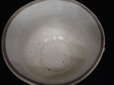 a white bowl sitting on a table with a black background