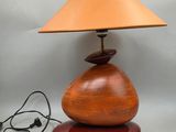 une image représentant une lampe avec un pied en bois et un abat-jour marron