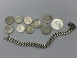 an assortment of silver coins and a silver chain on a table