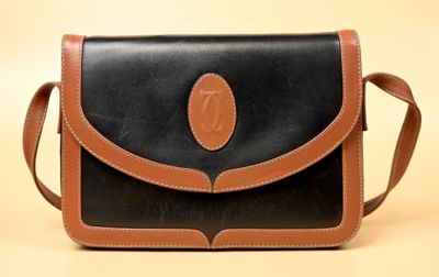 une image représentant un sac à main noir et marron sur fond beige