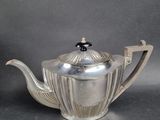 an antique silver teapot with a black lid on a table