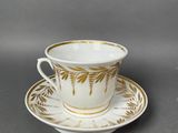 a white and gold cup and saucer on a gray surface