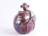 un vase violet sur lequel est perché un singe