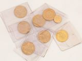 several gold coins in clear plastic bags on a white surface