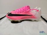 un gros plan d'une chaussure de football rose et noire posée sur une surface blanche