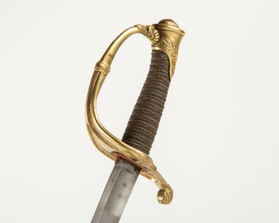 un gros plan d'une épée à la poignée dorée sur fond blanc