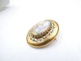 an image of a broochle with a white and yellow stone in it