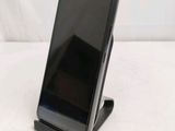 a black cell phone on a stand on a white surface