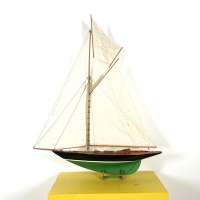 une petite maquette de voilier posée sur un socle jaune