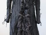 un manteau noir à col de fourrure posé sur un présentoir pour mannequin