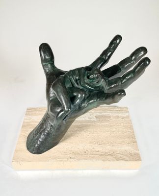 statue représentant une main tenant une fleur, posée sur un socle en marbre