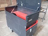 a black tool box with a red seat on wheels