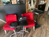 two red chairs and a black stool in a room